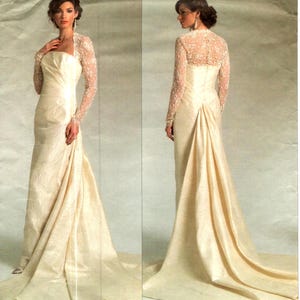 May include: A floor-length cream-coloured gown featuring a strapless bodice with a textured fabric finish and long, sheer lace sleeves. The dress includes a fitted waistline that transitions into a flowing skirt with a train, visible from both front and back.