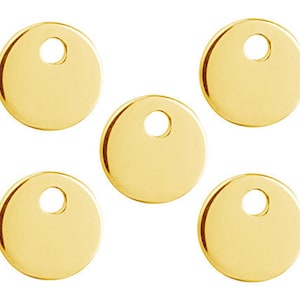 May include: Five gold-colored metal round disc charms with a hole in the center.
