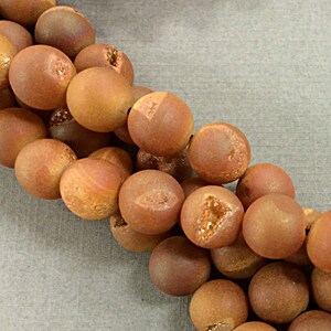 May include: A strand of round, brown agate beads with a slightly rough, textured surface. The beads have a natural, earthy look.