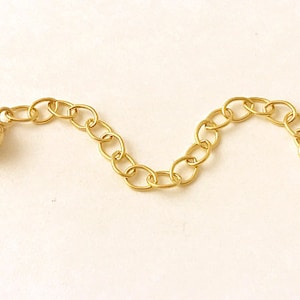 May include: A gold chain extender with a round ball at one end. The chain is made of small, linked circles.