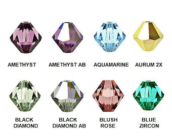 May include: Eight faceted crystal beads in various colors, including amethyst, aquamarine, and blush rose. Each bead has a hole for stringing. The text below each bead identifies the color: AMETHYST, AMETHYST AB, AQUAMARINE, AURUM 2X, BLACK DIAMOND, BLACK DIAMOND AB, BLUSH ROSE, and BLUE ZIRCON.
