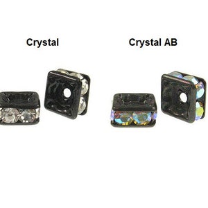 May include: Two black square bead spacers with a hole in the center. One spacer has clear crystals and the other has iridescent crystals.