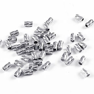 May include: A pile of silver metal crimp beads, with a twisted or spiral design. The beads are small and cylindrical.