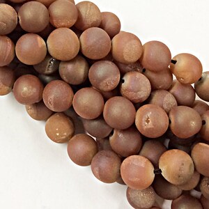 May include: A strand of brown agate beads with a matte finish. The beads are round and have a slightly irregular shape.
