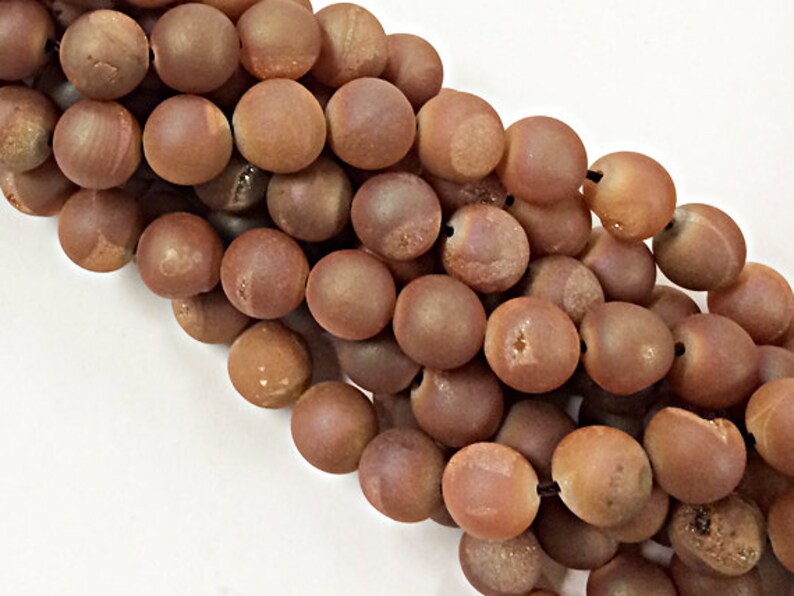 May include: A strand of brown agate beads with a matte finish. The beads are round and have a slightly irregular shape.