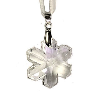 Swarovski Magic Classic Crystal snowflake ornament .A silver snowflake pendant necklace with a clear crystal snowflake charm. The necklace has a white satin ribbon.