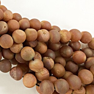 May include: A strand of brown agate beads with a matte finish. The beads are round and have a natural, earthy look.