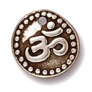 May include: Silver charm with an Om symbol in a circle with a beaded border.