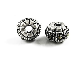 May include: Two silver and black bead spacers with a round shape and a hole in the center. The beads have a textured surface and are decorated with small black and gold accents.