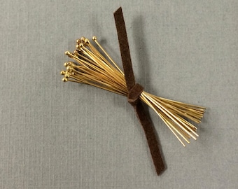 May include: A bundle of gold-colored head pins with round heads, tied together with a brown ribbon.