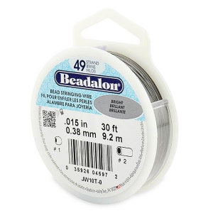 May include: A spool of silver Beadalon bead stringing wire. The label reads "Beadalon Bead Stringing Wire", "0.015 in 0.38 mm", "30 ft 9.2 m", "Bright Brilliant Brillante", and "JW10T-0".