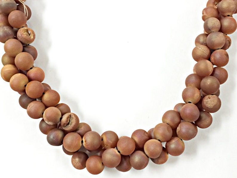 May include: A strand of brown agate beads, each bead is round and smooth. The beads are strung on a clear thread.