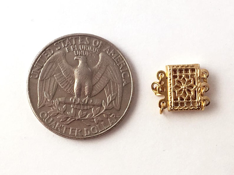 May include: Gold-toned metal clasp with a decorative design. The clasp is about the size of a US quarter.