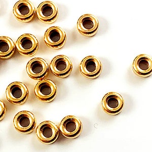 K&ouml;nnte beinhalten: Eine Sammlung von goldfarbenen Metall-Spr&uuml;hringen. Die Ringe sind alle gleich gro&szlig; und in einem zuf&auml;lligen Muster angeordnet.