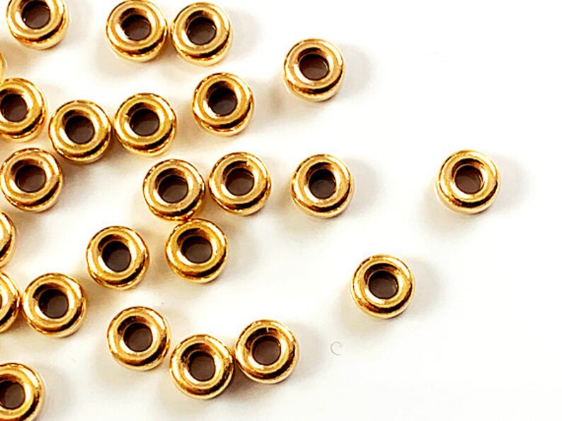 K&ouml;nnte beinhalten: Eine Sammlung von goldfarbenen Metall-Spr&uuml;hringen. Die Ringe sind alle gleich gro&szlig; und in einem zuf&auml;lligen Muster angeordnet.