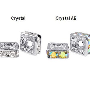 May include: Two silver square bead spacers with crystal rhinestones. The spacer on the left has clear crystals, and the spacer on the right has iridescent AB crystals.
