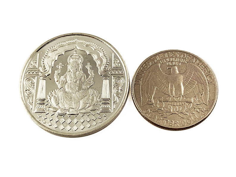 Fine Silver Ganesh coin depicting Ganesh , the elephant god in the center, Ganesh Pure silver coin in 10 gm for diwali, puja wedding return gift. The coin features intricate detailing and Sanskrit text.  It's a round, silver-Silver collectible item, ideal for religious or cultural purposes. The design showcases the god in a seated position on a lotus flower,
Ganesh Pure silver coin fine silver 999 A silver coin with a raised image of the Hindu deity Ganesha sitting on a lotus flower.