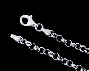 May include: Close-up of a silver-colored chain necklace with a lobster clasp. The chain is composed of round, interlocking links. The clasp and the end of the chain are visible, with markings that read "925 ITALY". The background is black.