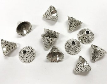 Peut inclure: Un groupe de 10 embouts de perles en métal argenté en forme de cône avec un bord festonné décoratif et une surface texturée.