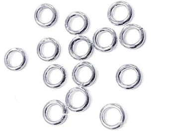 May include: A collection of silver jump rings, a type of jewelry finding used for connecting chains, cords, and other jewelry components.