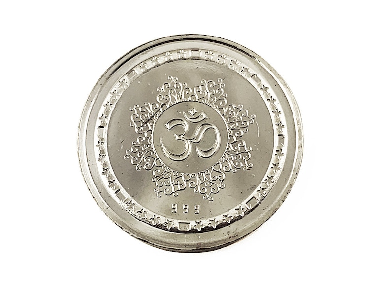 Fine Silver Ganesh coin depicting Ganesh , the elephant god in the center, Ganesh Pure silver coin in 10 gm for diwali, puja wedding return gift. The coin features intricate detailing and Sanskrit text.  It's a round, silver-Silver collectible item, ideal for religious or cultural purposes. The design showcases the god in a seated position on a lotus flower,
Ganesh Pure silver coin fine silver 999 A silver coin with a raised image of the Hindu deity Ganesha sitting on a lotus flower.