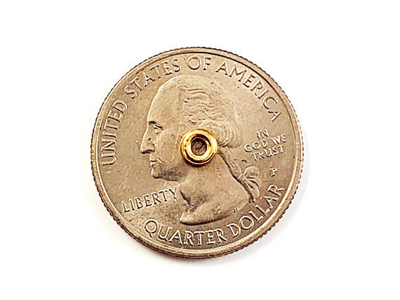 K&ouml;nnte beinhalten: Eine goldfarbene US-Viertel-Dollar-M&uuml;nze mit den Worten "United States of America" und "In God We Trust" darauf. Die M&uuml;nze zeigt ein Profil von George Washington und die Worte "Liberty" und "Quarter Dollar".