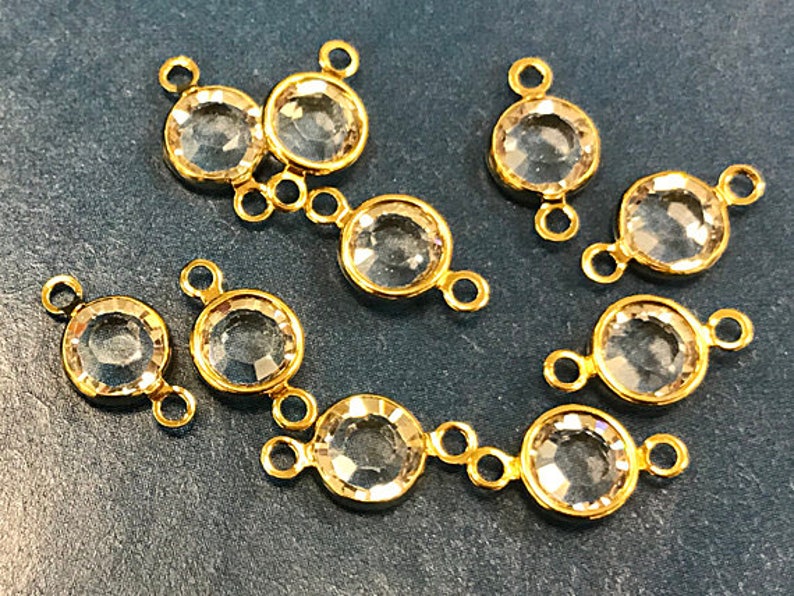 May include: Eight gold-tone connector charms with clear faceted glass stones. Each charm has two loops for attaching to jewellery.
