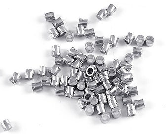 May include: A large pile of silver metal crimp beads. The beads are small and cylindrical in shape.