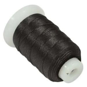 May include: A spool of black waxed thread for sewing leather. The thread is wound around a white plastic bobbin.