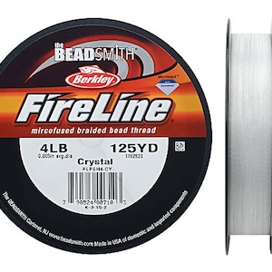 May include: A spool of clear FireLine microfused braided bead thread. The label reads "FireLine" in white and orange, with "4LB" and "125YD" measurements. The spool is black with white text and a barcode. The thread is crystal clear.