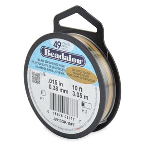 May include: A spool of 49 strand gold-plated beading wire. The wire is 0.015 inches thick and 10 feet long. The spool is labeled "Beadalon" and has a barcode and product number JW10GP-10FT.