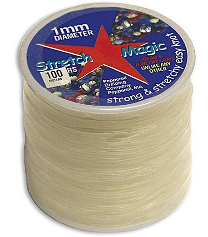 May include: A spool of clear, stretchy beading cord. The label reads "Stretch Magic" with a red star and blue background. The cord is 1 mm in diameter and 100 meters long, perfect for jewelry making. The packaging also states "strong & stretchy easy knot".