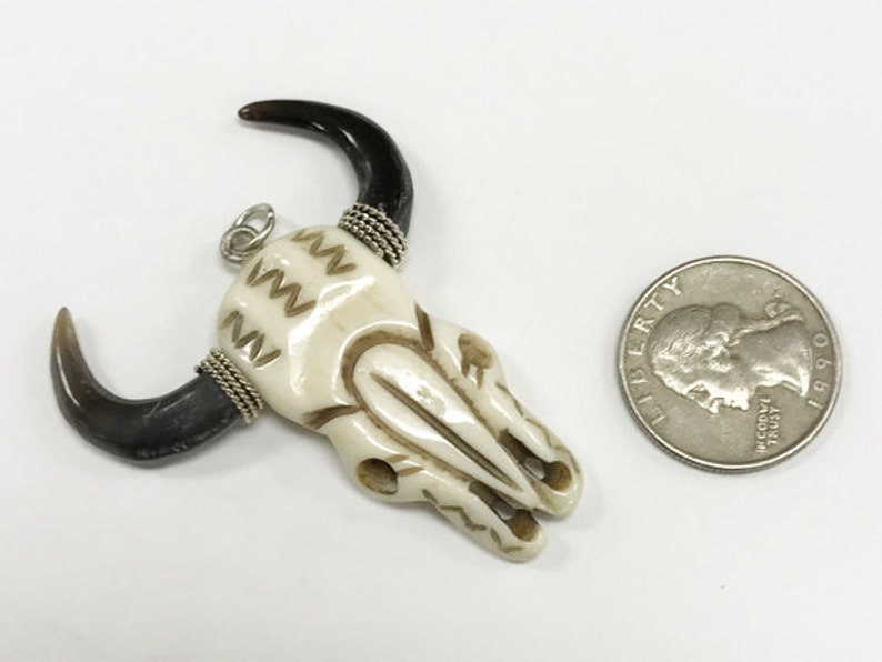 Peut inclure: Pendentif en os de cr&acirc;ne de taureau blanc avec des cornes noires et des accents de fil argent&eacute;. Le pendentif est &agrave; peu pr&egrave;s de la taille d'une pi&egrave;ce de 25 cents am&eacute;ricaine.