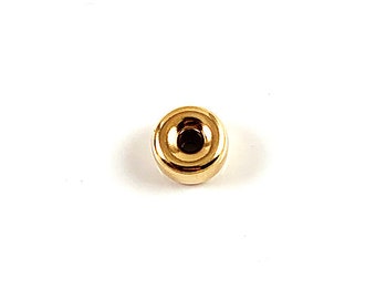 May include: A gold-colored metal bead with a round shape and a small hole in the center.