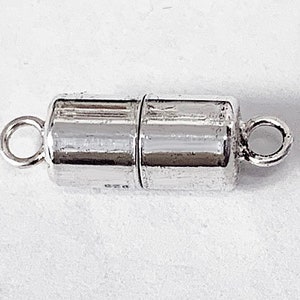 May include: Silver magnetic clasp for jewelry making. The clasp is made of two cylindrical pieces with a loop on each end. The pieces are magnetic and connect to each other.