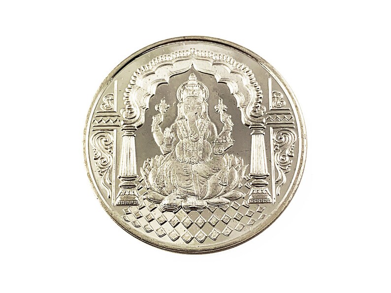 Fine Silver Ganesh coin depicting Ganesh , the elephant god in the center, Ganesh Pure silver coin in 10 gm for diwali, puja wedding return gift. The coin features intricate detailing and Sanskrit text.  It's a round, silver-Silver collectible item, ideal for religious or cultural purposes. The design showcases the god in a seated position on a lotus flower,
Ganesh Pure silver coin fine silver 999 A silver coin with a raised image of the Hindu deity Ganesha sitting on a lotus flower.