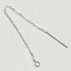 May include: Silver earring with a chain and a straight bar hanging from it.