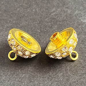 Op de afbeelding: Twee gouden metalen kralencaps met heldere strasssteentjes. Elke dop heeft een lus aan de zijkant en een schroefgat aan de bovenkant.