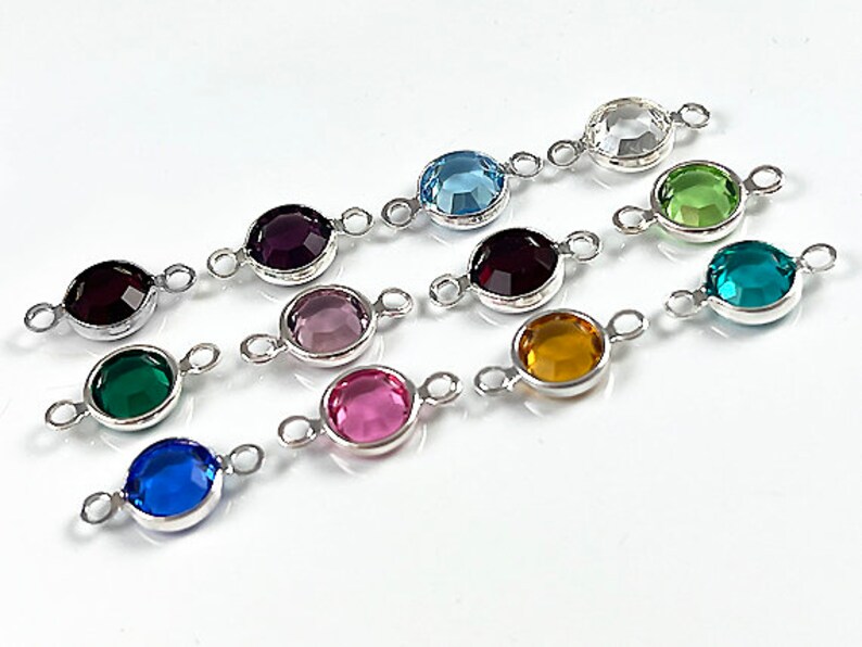 Puede incluir: Surtido de 10 dijes conectores plateados con piedras de cristal de diferentes colores. Cada dije tiene dos lazos para sujetar a las joyas.