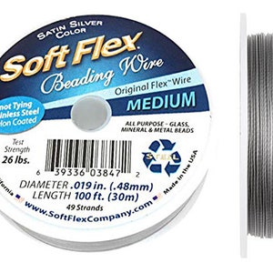 May include: A spool of silver Soft Flex beading wire, labeled "Satin Silver Color", "Original Flex Wire", "Medium", "All Purpose - Glass, Mineral & Metal Beads", "Test Strength 26 lbs.", "Diameter .019 in. (.48mm)", "Length 100 ft. (30m)", "49 Strands", "www.SoftFlexCompany.com", and "Made in the USA".