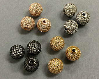 May include: A collection of round, faceted beads with a pave setting. The beads are available in gold, rose gold, silver, and black.