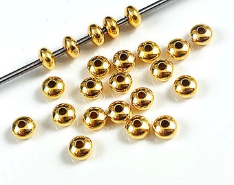 May include: A collection of gold-colored metal beads, some strung on a wire, others loose. The beads are round and have a flat, slightly indented top and bottom.