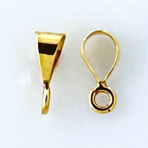 May include: Two gold-toned metal pendant bails. One bail is a simple loop with a round opening. The other bail is a flat, triangular shape with a loop at the bottom.