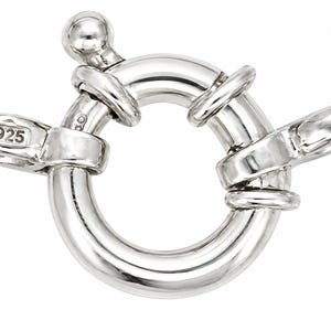 May include: A polished silver-tone spring ring clasp featuring a circular design with a small protruding lever and a ball-shaped end. The metal component includes a rectangular stamp clearly displaying the number 925, indicating sterling silver.