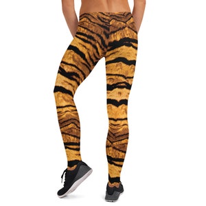 May include: Black and orange tiger print leggings. The leggings are form-fitting and have a high waist.