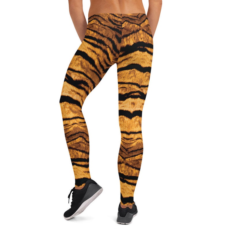 May include: Black and orange tiger print leggings. The leggings are form-fitting and have a high waist.