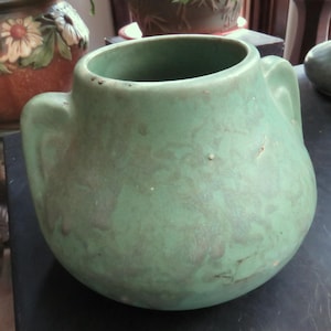 May include: A green ceramic vase with two handles. The vase has a mottled glaze and a rounded shape.