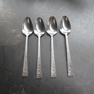 May include: Four silver spoons with an ornate floral design. The spoons have a rounded bowl and a long, slender handle.