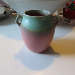 May include: A green and pink glazed ceramic vase with two handles. The vase is round and has a wide mouth.