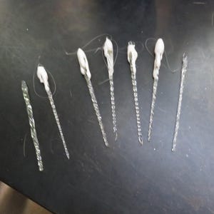 May include: Eight white glass ornaments with a twisted design. The ornaments are approximately 10 inches long.